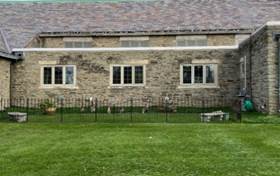 A brick building with a fence and grass in front of it

Description automatically generated with low confidence